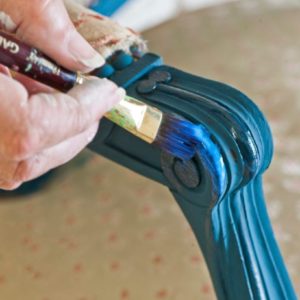 Annie Sloan applying Gold Size to a chair painted with Chalk Paint® in Aubusson Blue