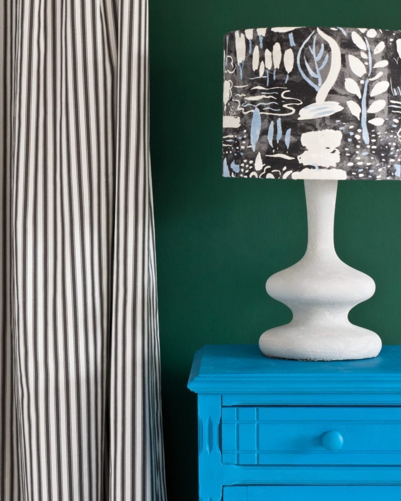 Side table painted with Chalk Paint® in Giverny, a bright, clean, cool blue against a wall of Amsterdam Green. Ticking in Graphite curtain and Dulcet in Graphite lampshade