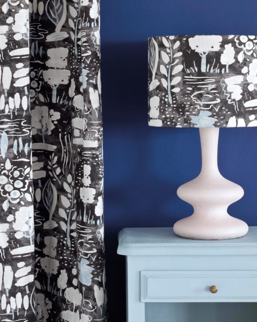 Side table painted with Chalk Paint® in Louis Blue, a clean pastel blue against a wall of Napoleonic Blue. Curtain and lampshade in Dulcet in Graphite