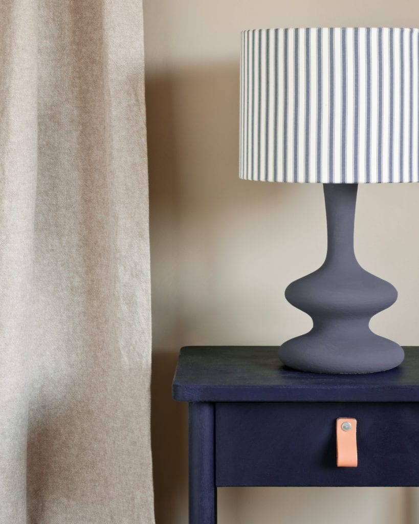 Side table painted with Chalk Paint® in Oxford Navy, an inky, traditional navy blue against a wall of Country Grey. Curtain Linen Union in Old White + French Linen and lampshade in Ticking in Old Violet