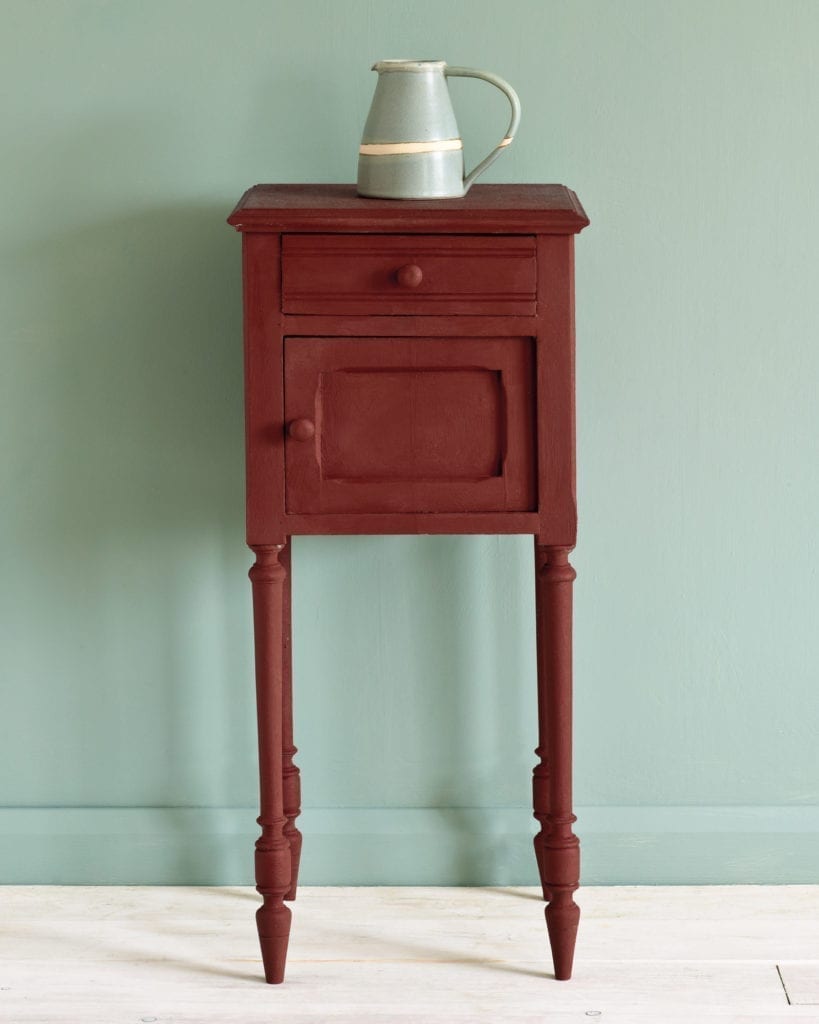 Side table painted with Chalk Paint® in Primer Red, a deep, red ochre against a wall of Duck Egg Blue