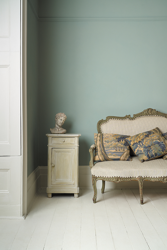 Pemberly Blue Wall Paint by Annie Sloan used on a wall behind a vintage loveseat