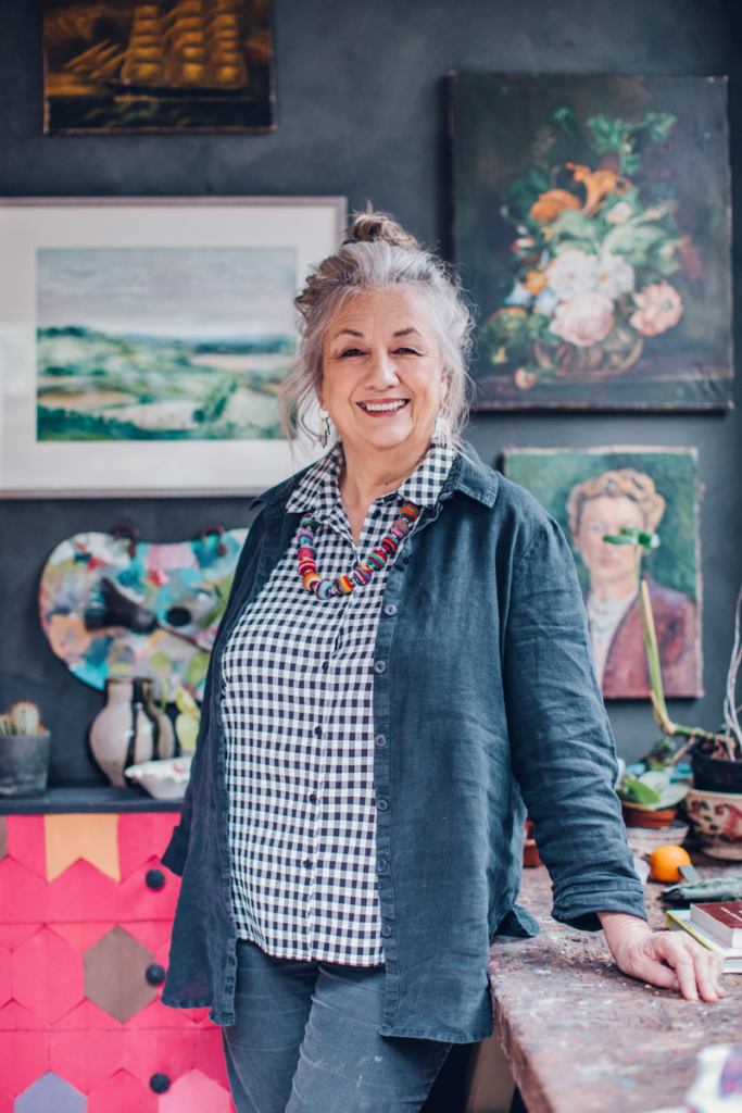 Annie Sloan Posing in her Studio surrounded by Paintings for Create Academy