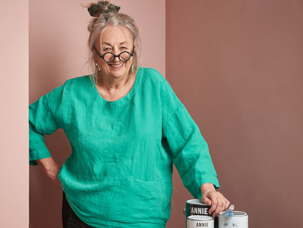 Annie Sloan smiling and standing in front of Piranesi Pink painted wall