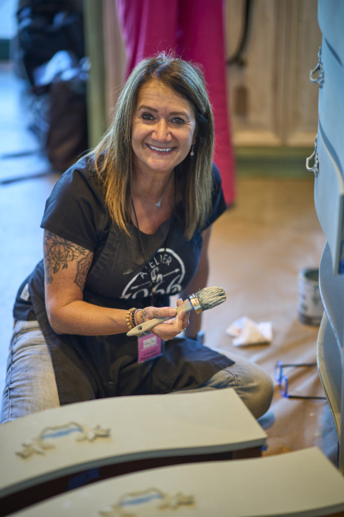 Furniture painter Atelier 1996, smiling and painting a piece of furniture at the Big Paint event in New Orleans