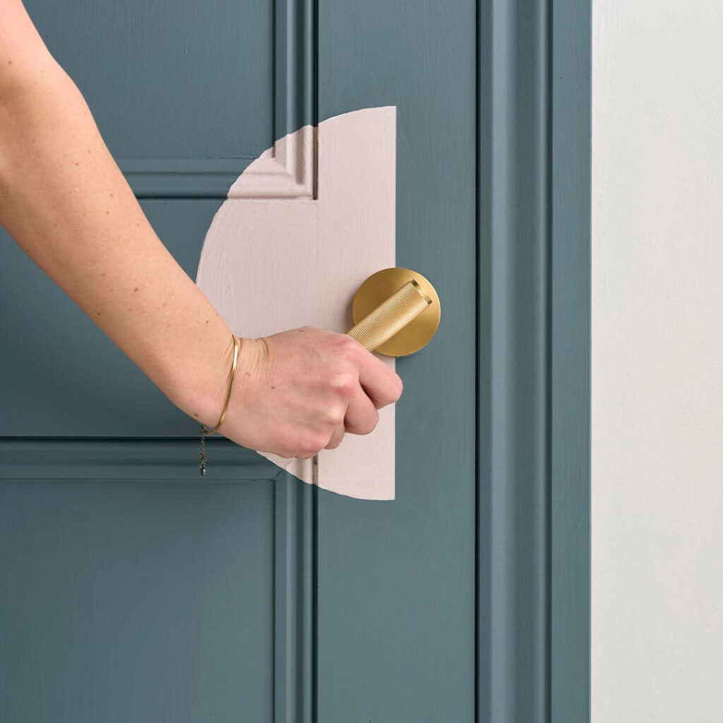 Hand pushing down door handle on painted door