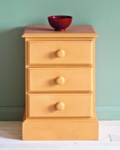 Side table painted with Chalk Paint® in Arles, a light, glowing orange-yellow against a wall of Duck Egg Blue