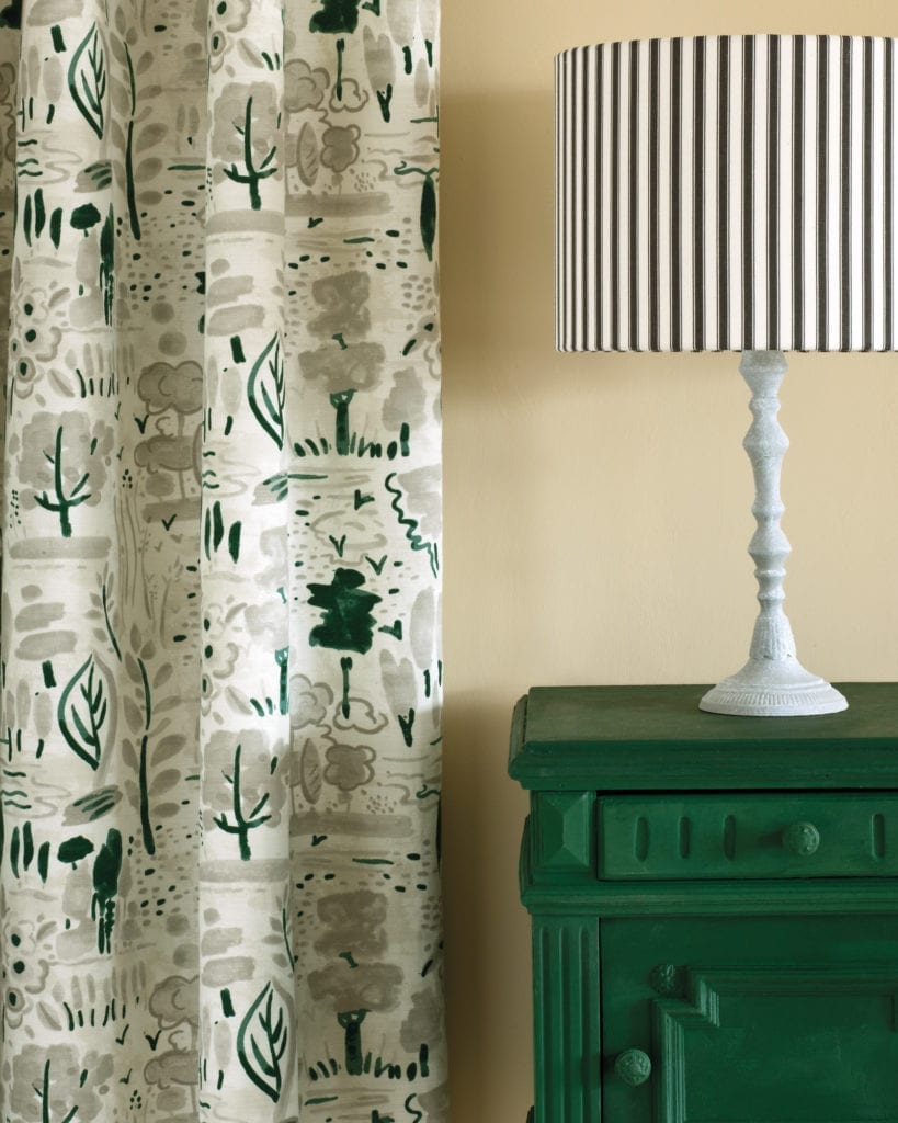 Side table painted with Chalk Paint® in Amsterdam Green, a strong, deep forest green. Curtain in Dulcet in Old White and Ticking in Graphite lampshade