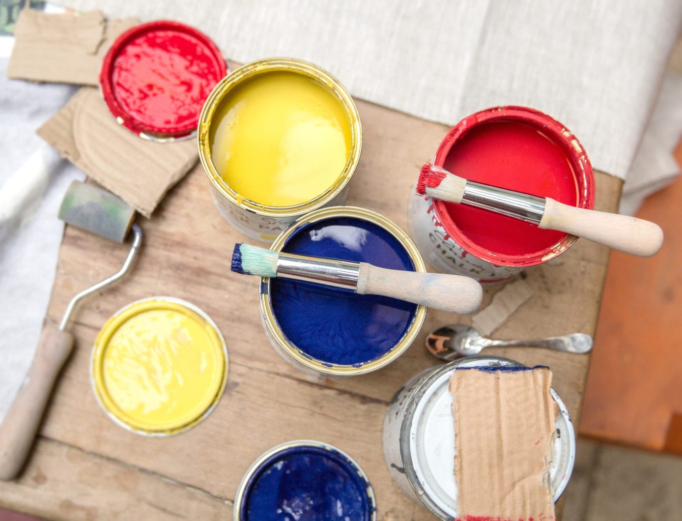Stencil Brushes by Annie Sloan resting on Chalk Paint tins in English Yellow, Emperor's Silk and Napoleonic Blue