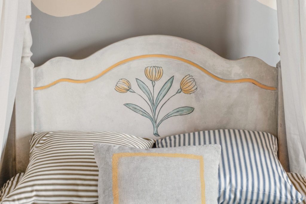 Swedish style four poster bed painted with Chalk Paint® by Annie Sloan in a tulip design. Cushions in Ticking fabrics