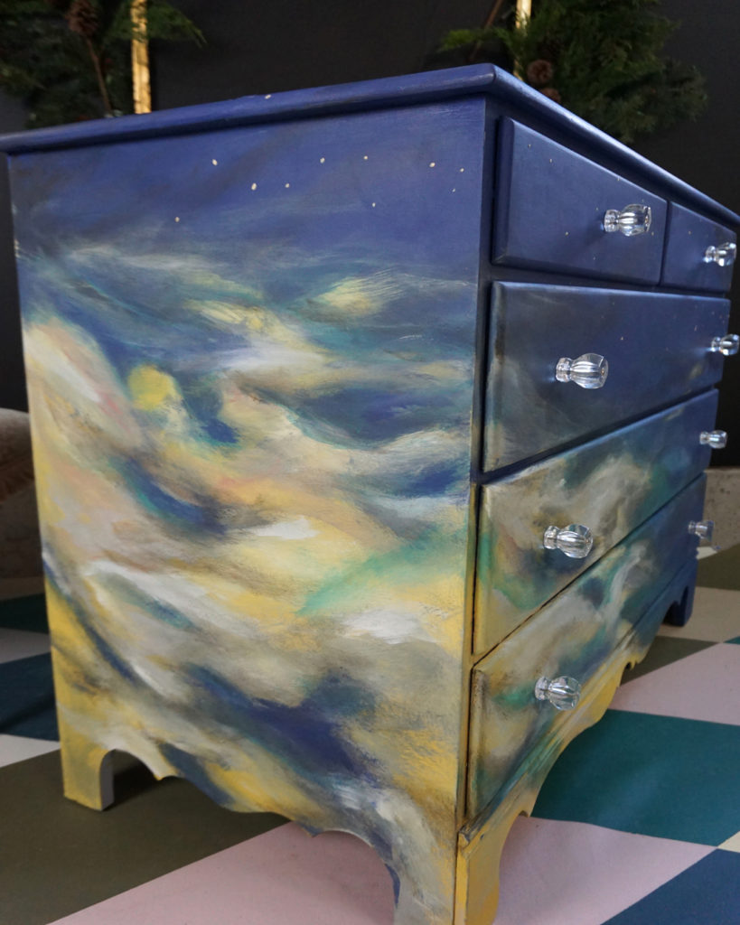 Une commode à tiroirs sur le thème du ciel peinte par l'artiste en résidence d'Annie Sloan, Olivia Lacy de l'atelier Pigeon and Pip