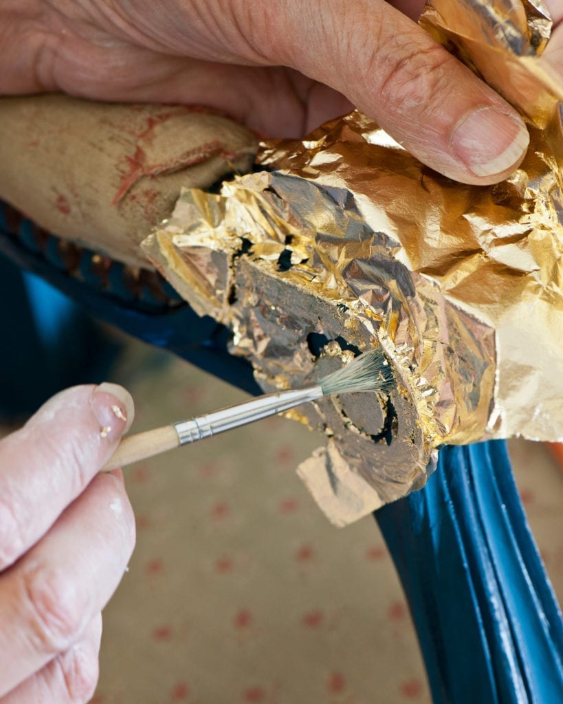 Annie Sloan applying brass leaf to a chair painted with Chalk Paint® in Aubusson Blue