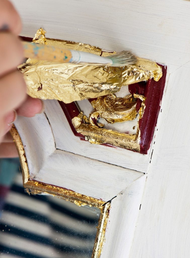 Brass Loose Leaf being applied to a mirror painted with Chalk Paint in Bugundy and Old White Credit CICO BOOKS Christopher Drake