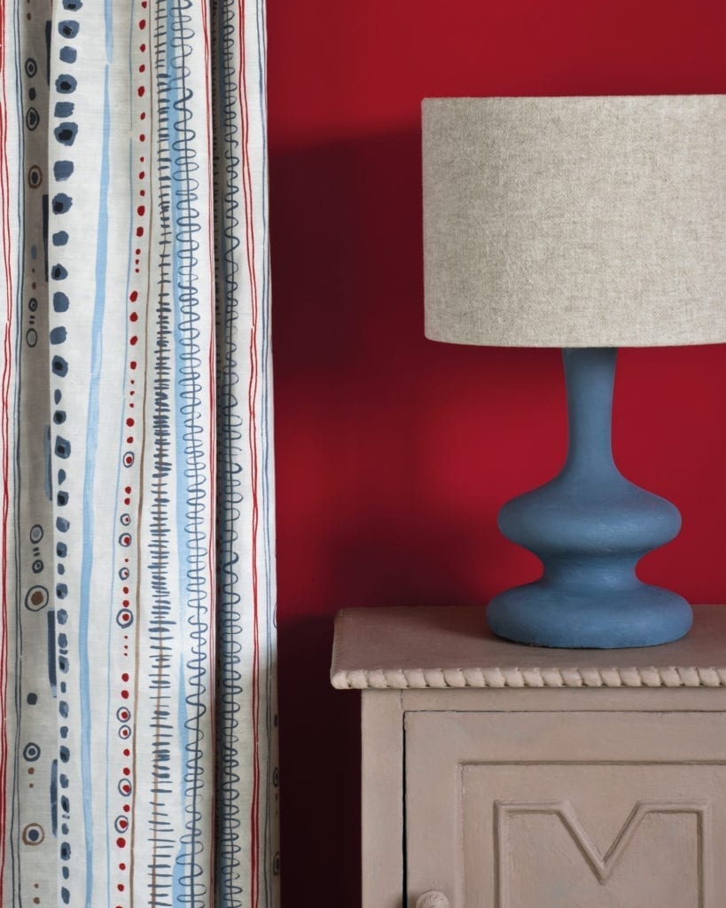 Side table painted with Chalk Paint® in Coco, a soft brown grey against a red wall of Emperor's Silk. Curtain in Piano in Old Violet and lampshade in Linen Union in Old White + French Linen