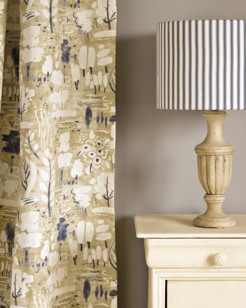 Side table painted with Chalk Paint® in Cream, a soft creamy yellow against a wall of French Linen. Dulcet in Versailles curtain and Ticking in Old Violet lampshade