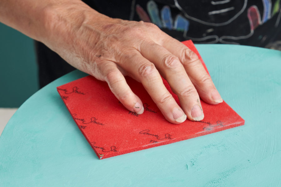 Annie Sloan's hand using her Sanding Pad on a Chalk Paint® surface