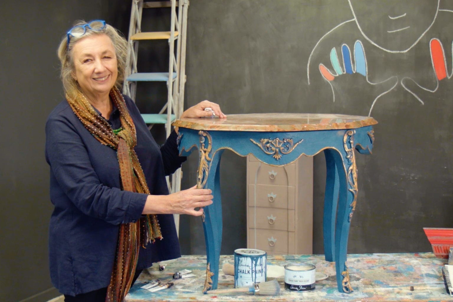 Annie Sloan gilding a table painted with Chalk Paint® furniture paint in Aubusson Blue and gilded with Bright Gold Gilding Wax