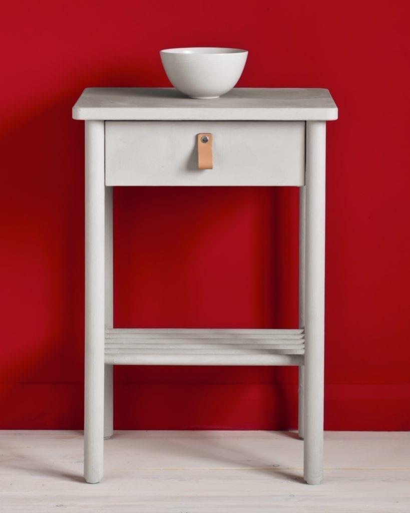 Side table painted with Chalk Paint® in Chicago Grey, a cool, fresh and modern grey, with a hint of blue against a red wall painted with Emperor's Silk