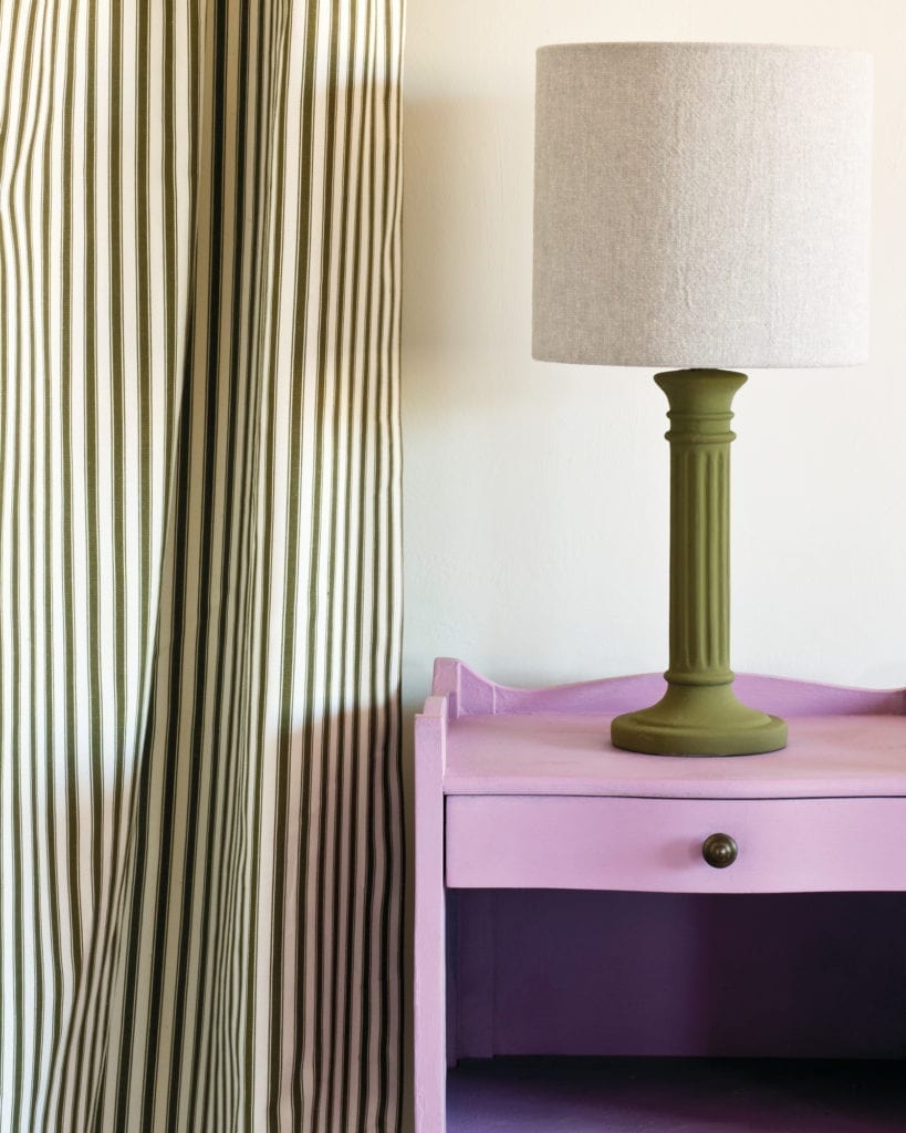 Side table painted with Chalk Paint® in Henrietta, a rich and complex pink with a hint of lilac. Curtain in Ticking in Olive and lampshade in Linen Union in Old White + French Linen