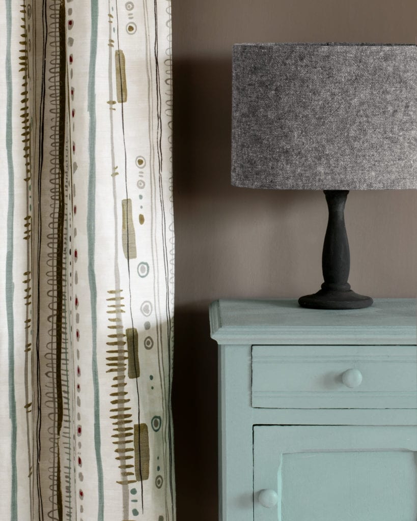 Side table painted with Chalk Paint® in Svenska Blue, a crisp and cool toned blue-grey against a wall of French Linen. Piano in Olive curtain and Linen Union in Graphite + Old White lampshade