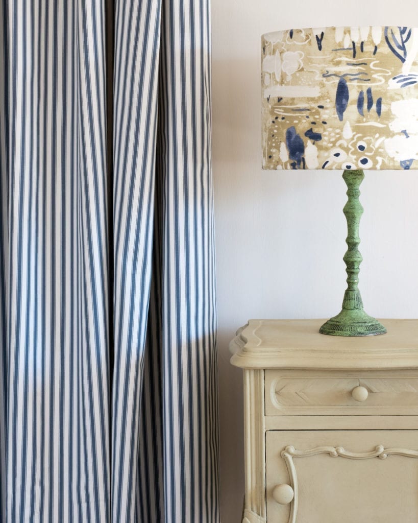 Side table painted with Chalk Paint® in Versailles, a soft, delicate, lightly yellowed dusky green a soft, delicate, lightly yellowed dusky green. Curtain in Ticking in Old Violet and Dulcet in Versailles lampshade