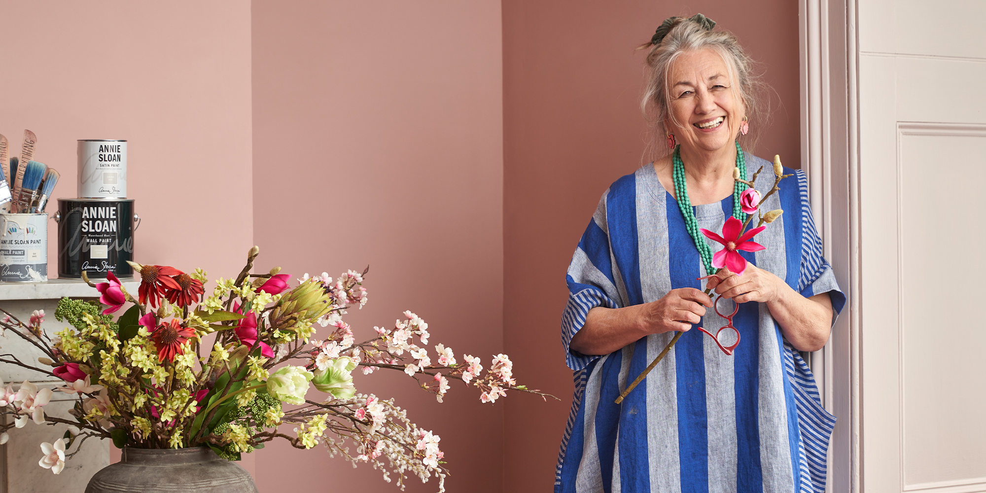 Annie Sloan holding a flower in front of a wall painted in Piranesi