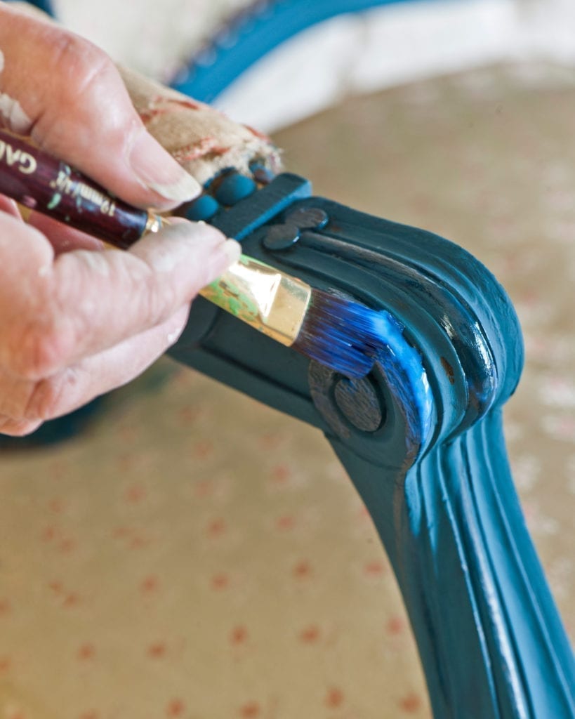 Annie Sloan applying Gold Size to a chair painted with Chalk Paint® in Aubusson Blue