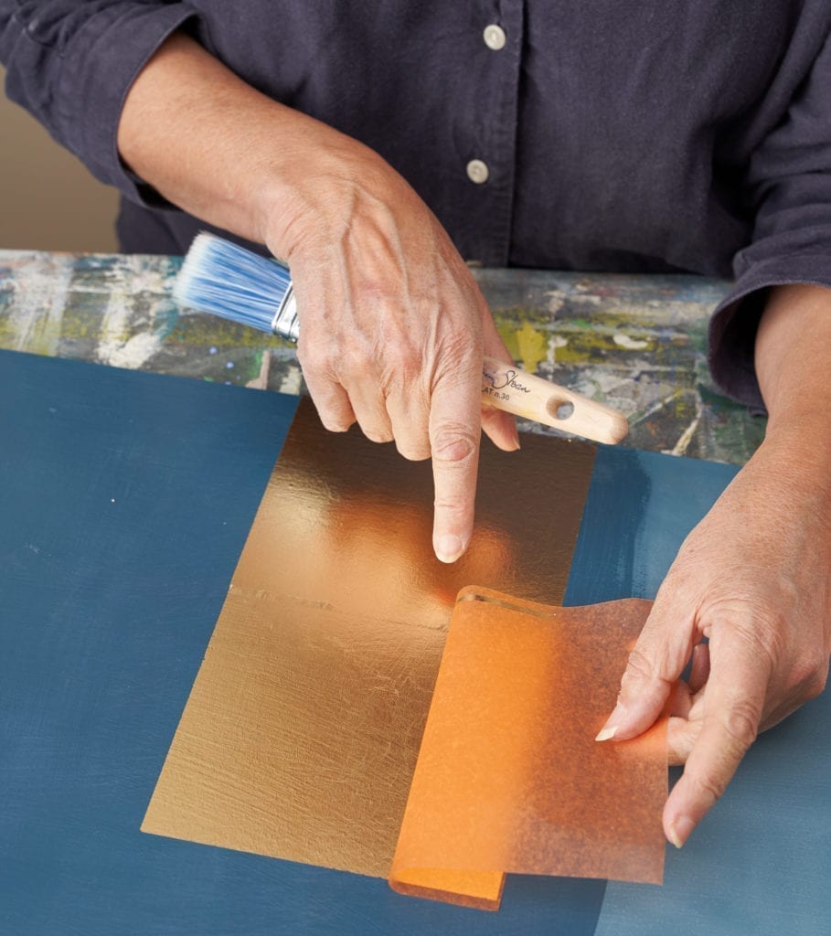 Annie Sloan applying Transfer Brass Leaf to a board painted with Chalk Paint in Aubusson Blue