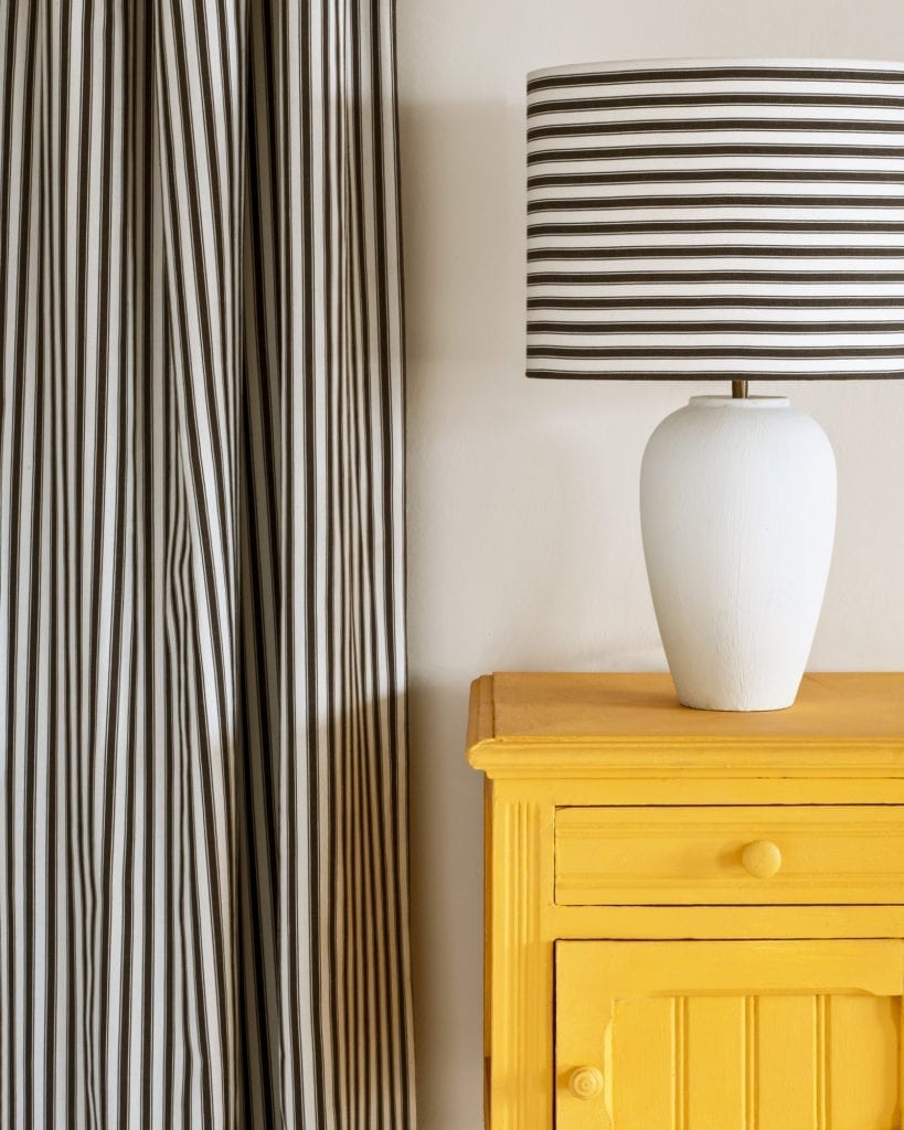 Side table painted with Chalk Paint® in Tilton, a bright, earthy mustard yellow. Ticking in Graphite curtain and lampshade