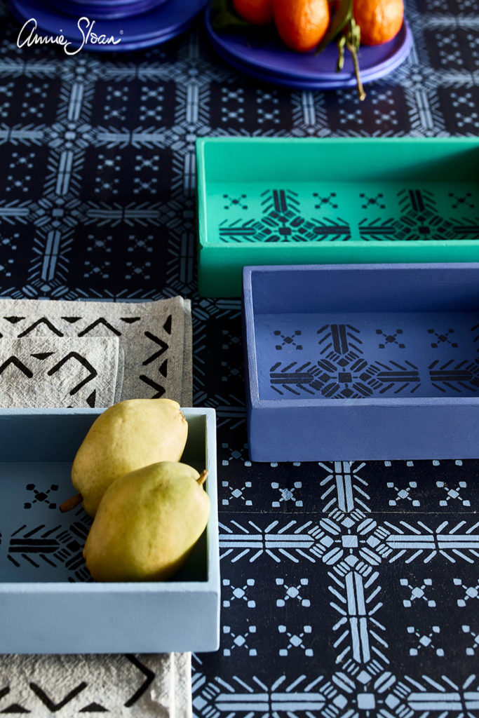 Close up of the Oxford Navy Chalk Paint® mediterranean style stencilled table with stencilled trays in Florence and Napoleonic Blue and some fruit to accessorise.